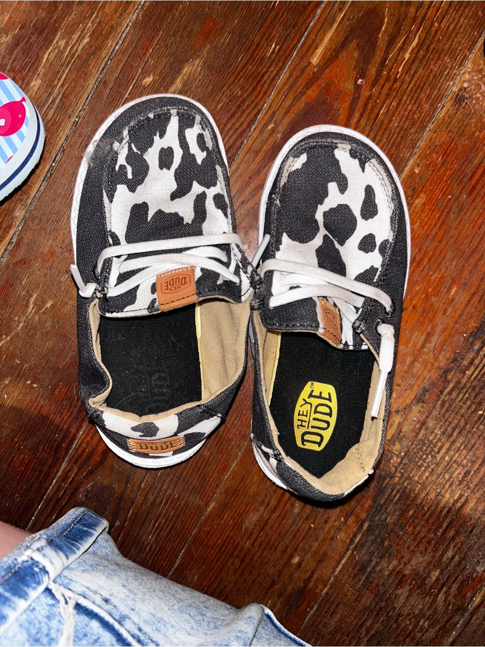 Hey Dude Kids Cow Print Slip-Ons in Black & White with Tan Accents